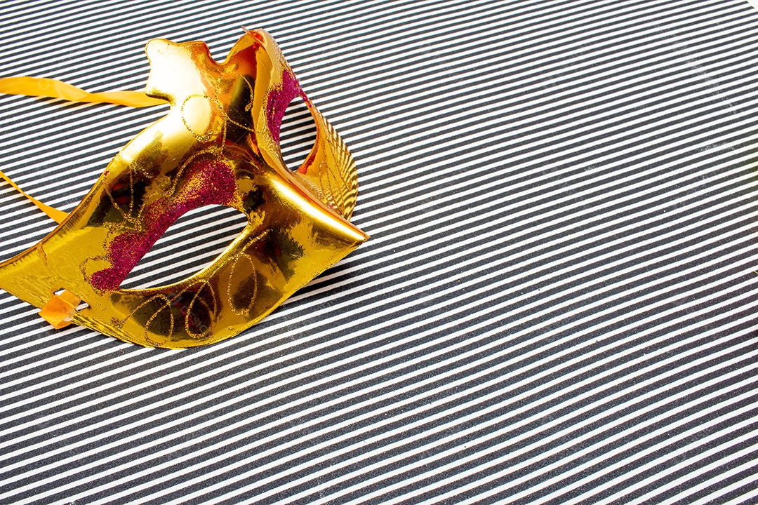 máscara de carnaval dourada em um fundo listrado preto e branco