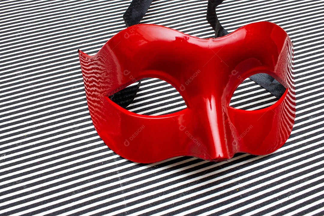 máscara de carnaval vermelha em um fundo listrado preto e branco