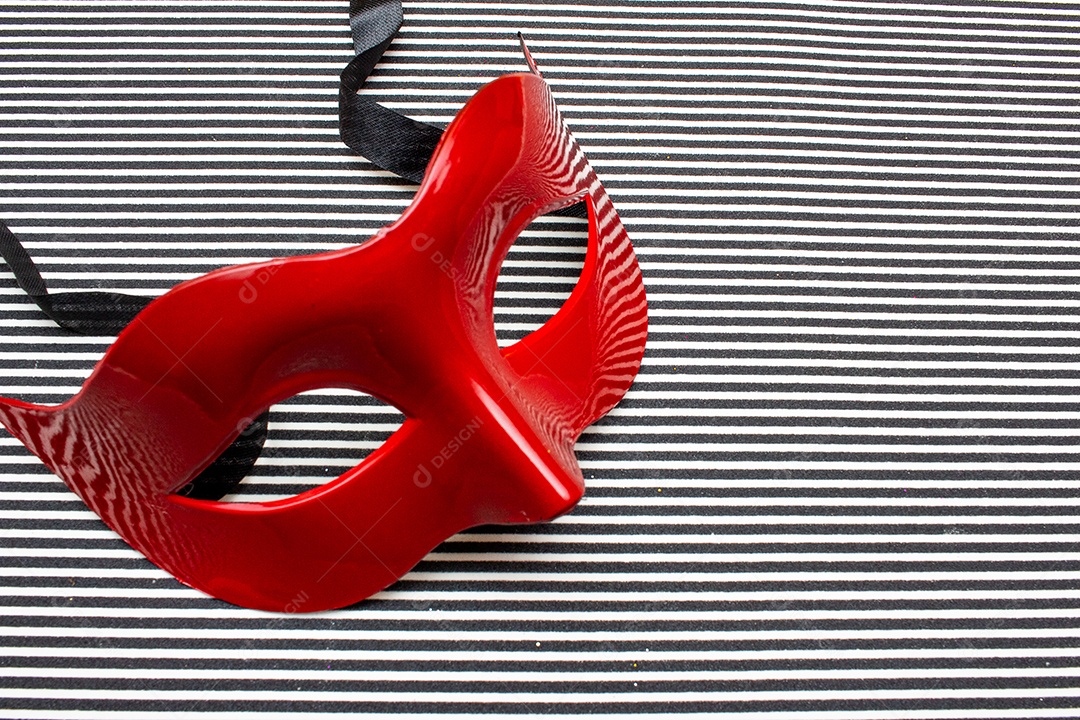 máscara de carnaval vermelha em um fundo listrado preto e branco