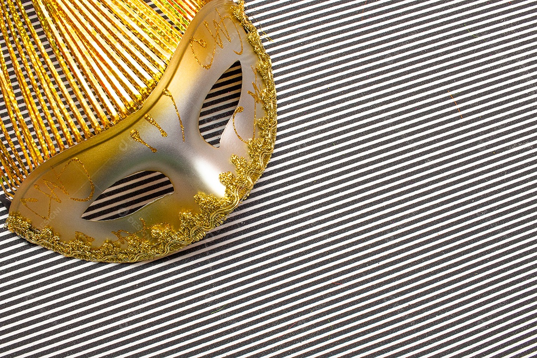máscara de carnaval dourada em um fundo listrado preto e branco