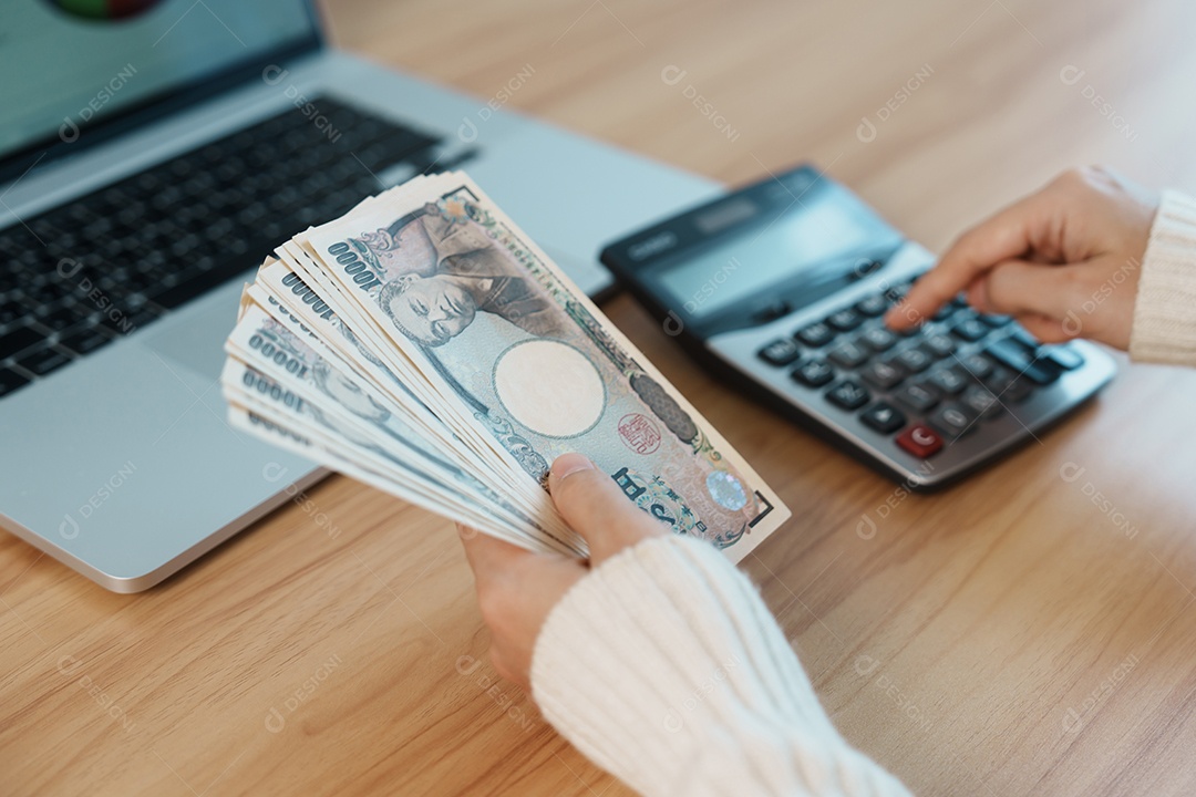 Mão de mulher contando notas de ienes japoneses com calculadora.