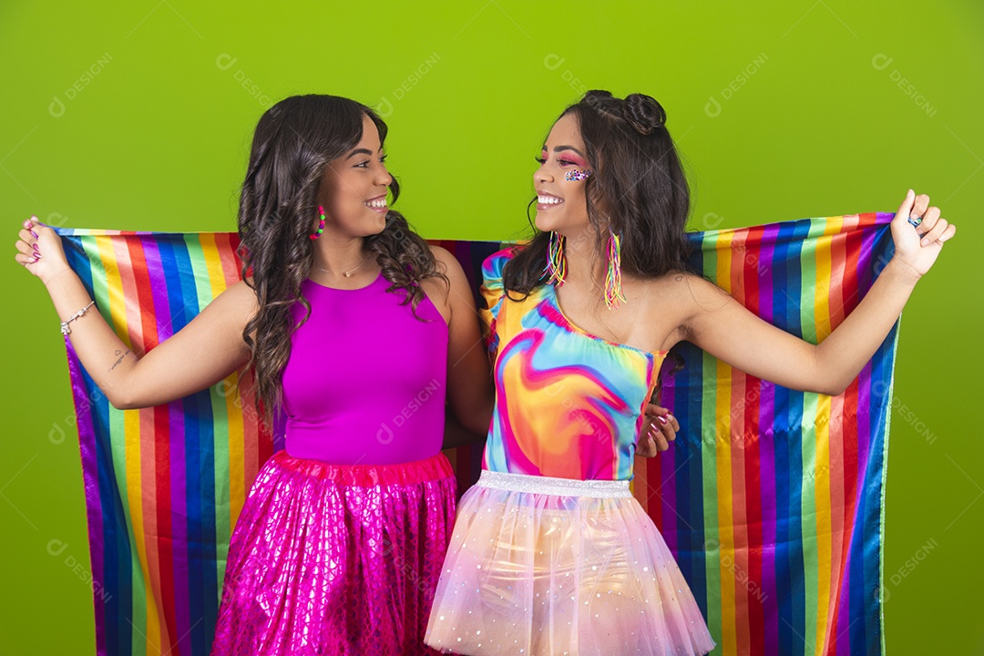 Lindas mulheres jovens segurando bandeira LGBTQI+ usando fantasia de carnaval sobre fundo isolado