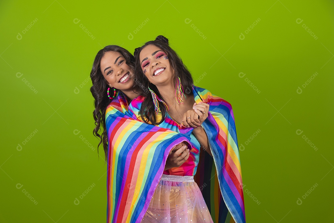 Lindas mulheres jovens segurando bandeira LGBTQI+ usando fantasia de carnaval sobre fundo isolado