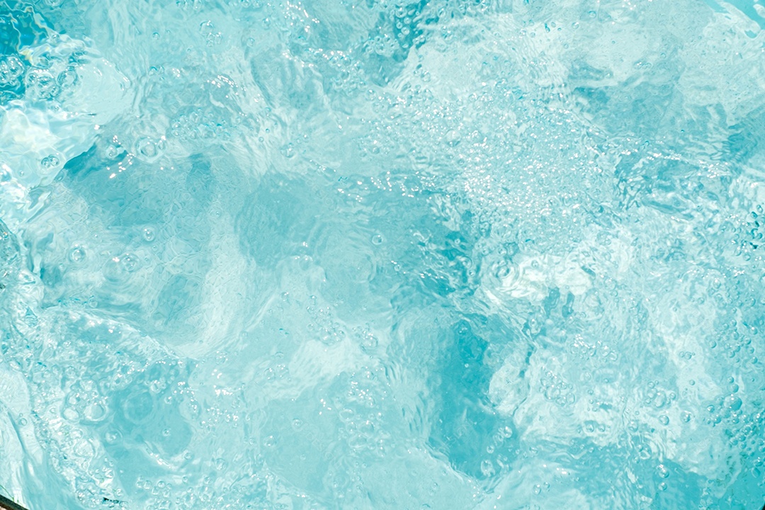 Textura de superfície de água calma transparente de cor azul turva com salpicos e bolhas. Fundo de natureza abstrata na moda. Ondas de água na luz solar. fundo de água