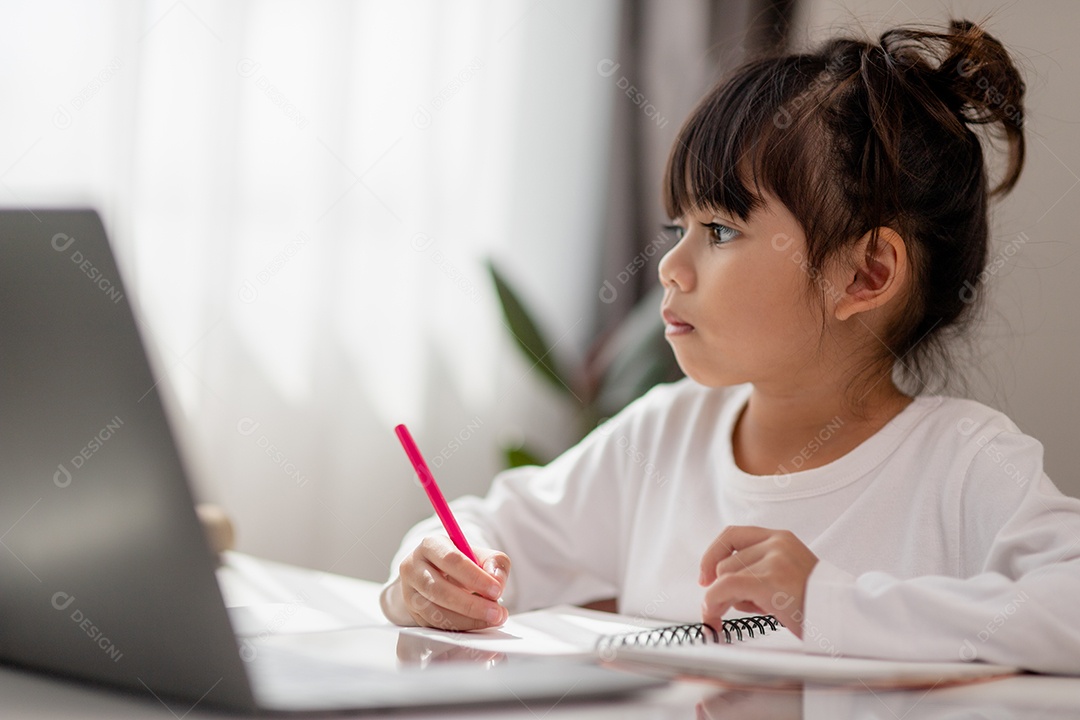 Aluna asiática fazendo sua lição de casa com o laptop em casa. As crianças usam aparelhos para estudar. Educação e ensino a distância para crianças. Educação domiciliar durante a quarentena. Ficar em casa