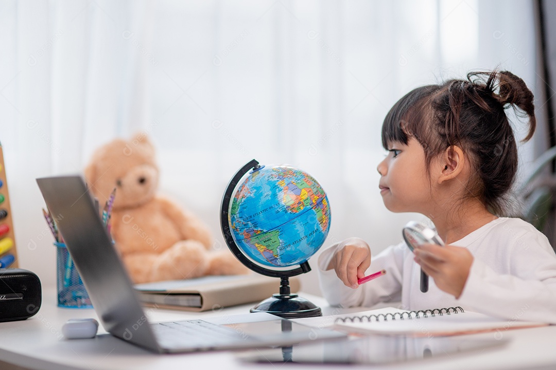 Aluna asiática fazendo sua lição de casa com o laptop em casa. As crianças usam aparelhos para estudar. Educação e ensino a distância para crianças. Educação domiciliar durante a quarentena. Ficar em casa