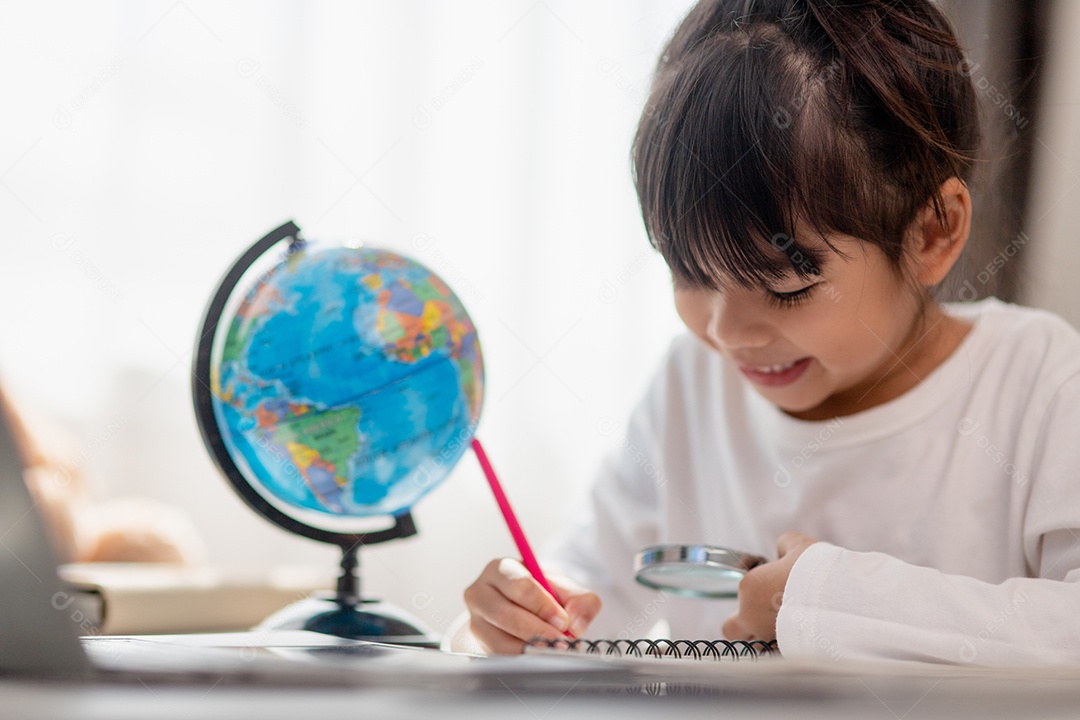 Aluna asiática fazendo sua lição de casa com o laptop em casa. As crianças usam aparelhos para estudar. Educação e ensino a distância para crianças. Educação domiciliar durante a quarentena. Ficar em casa