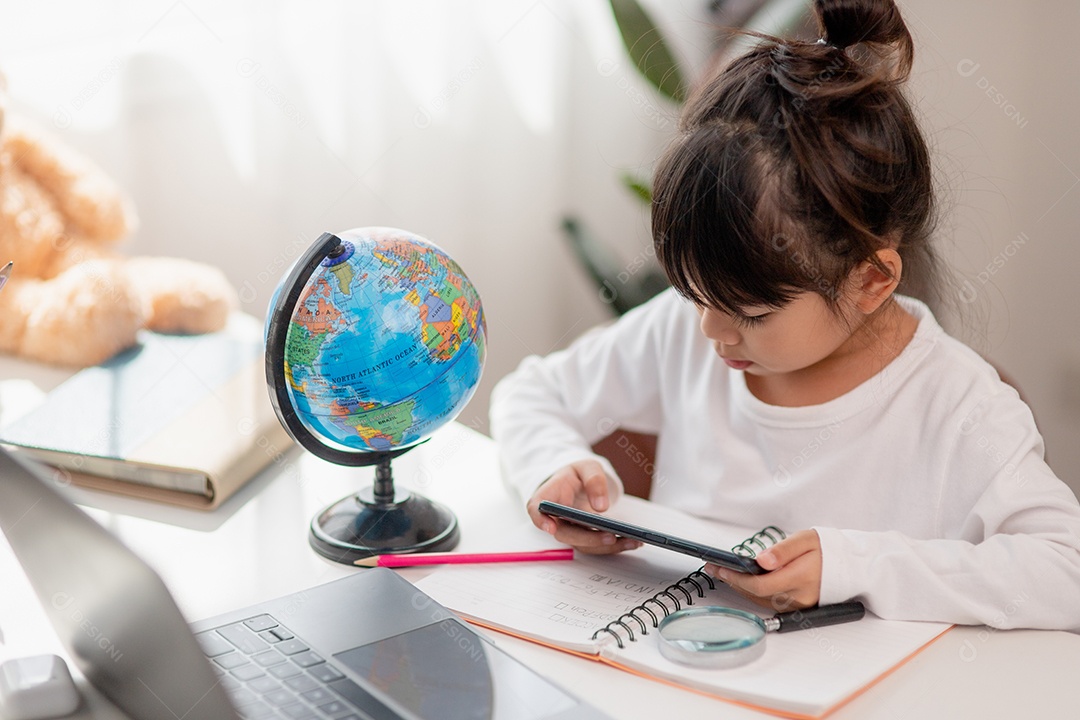 Aluna asiática fazendo sua lição de casa com o laptop em casa. As crianças usam aparelhos para estudar. Educação e ensino a distância para crianças. Educação domiciliar durante a quarentena. Ficar em casa