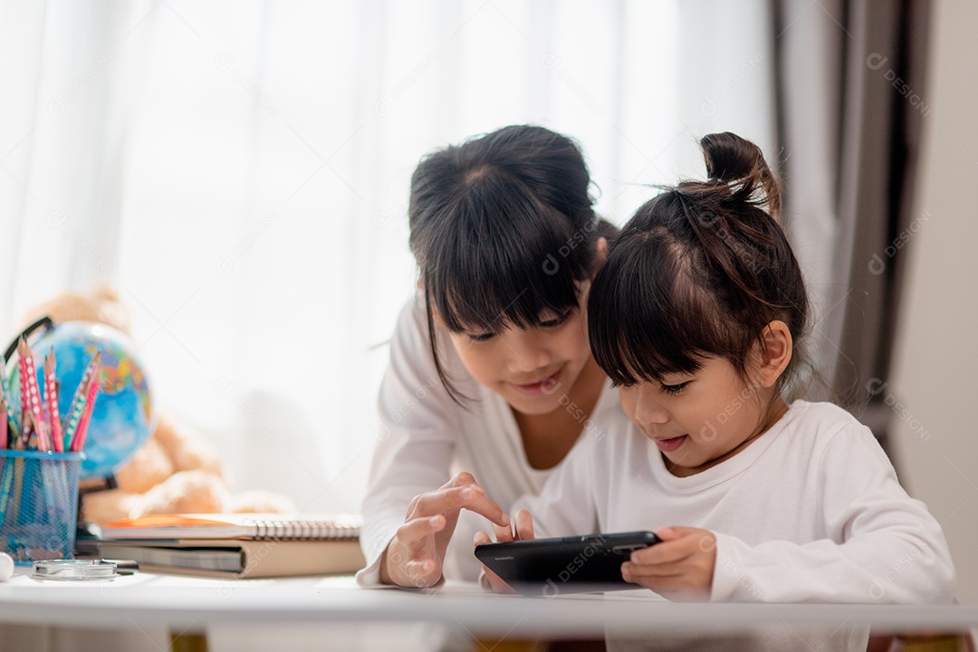 Crianças de conceito e gadgets. Duas irmãs irmãs olham para o telefone e sorriem. Eles seguram um smartphone, assistem a vídeos, aprendem, jogam, falam online. Internet para crianças. Controle dos pais