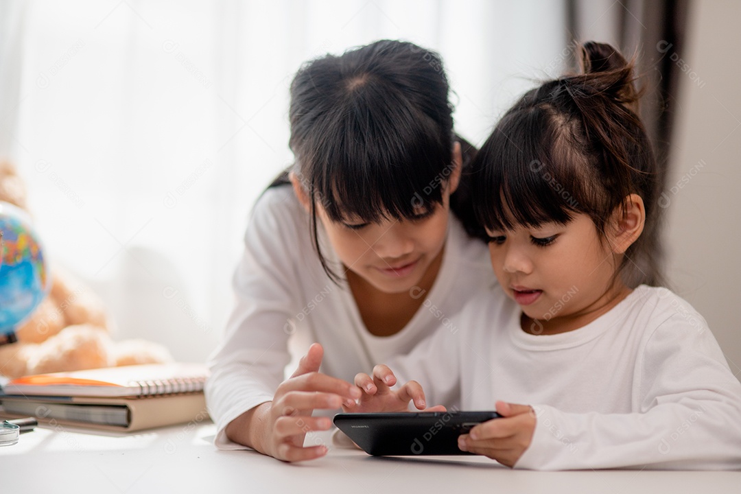 Crianças de conceito e gadgets. Duas irmãs irmãs olham para o telefone e sorriem. Eles seguram um smartphone, assistem a vídeos, aprendem, jogam, falam online. Internet para crianças. Controle dos pais