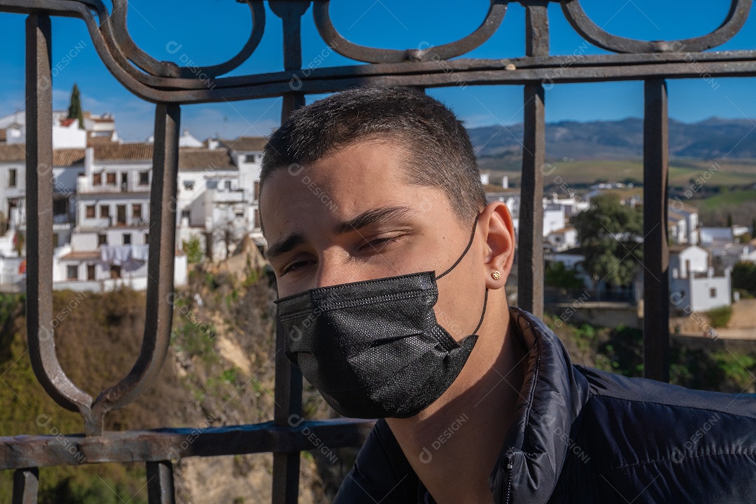 Vista de um jovem entediado usando máscara facial com o desfiladeiro de Ronda ao fundo