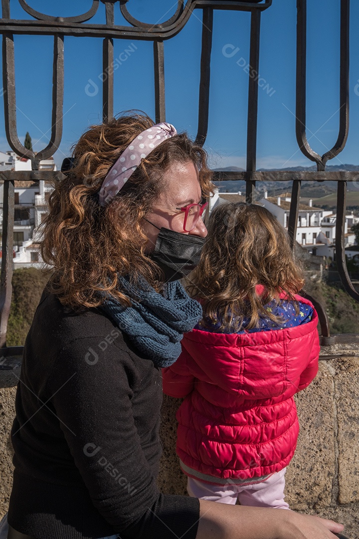Bela vista de mãe e filha usando máscara facial com desfiladeiro Ronda ao fundo.