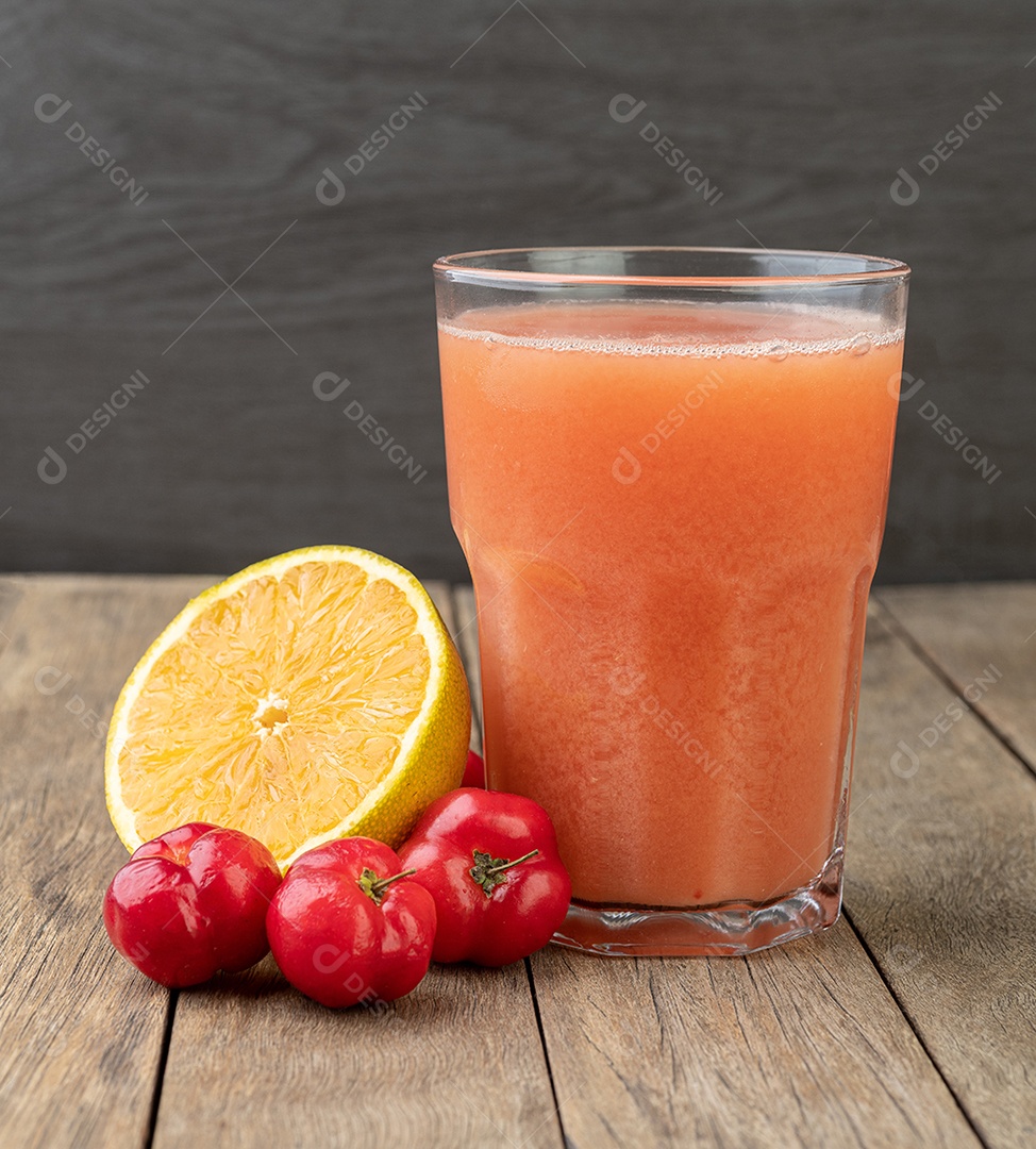 Acerolas ou cerejas de Barbados e suco de laranja com frutas sobre a mesa de madeira.