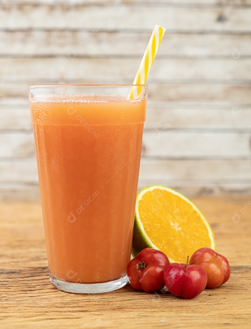 Acerolas ou cerejas de Barbados e suco de laranja com frutas sobre a mesa de madeira.