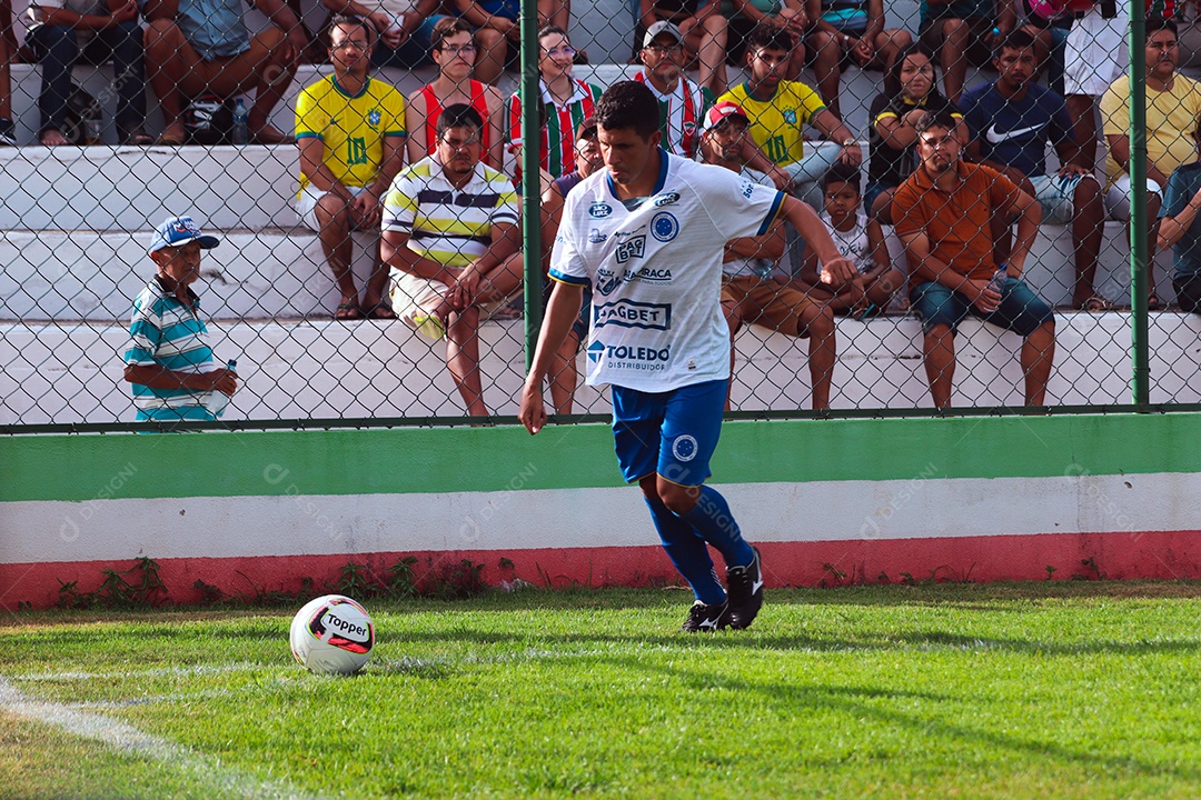 Belo homem jogando futebol sobre um gramado com torcida sobre fundo