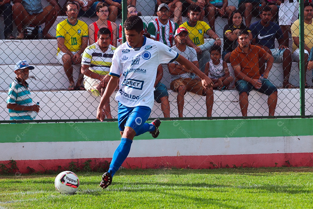 Belo homem jogando futebol sobre um gramado com torcida sobre fundo