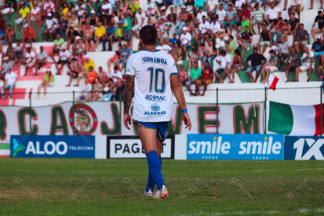 Belo homem jogando futebol sobre um gramado com torcida sobre fundo