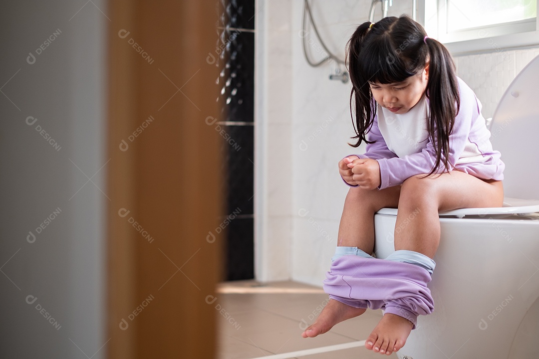 Linda garota asiática de pijama e calça desabotoada nas pernas sentada no banquinho no vaso sanitário de manhã depois de acordar