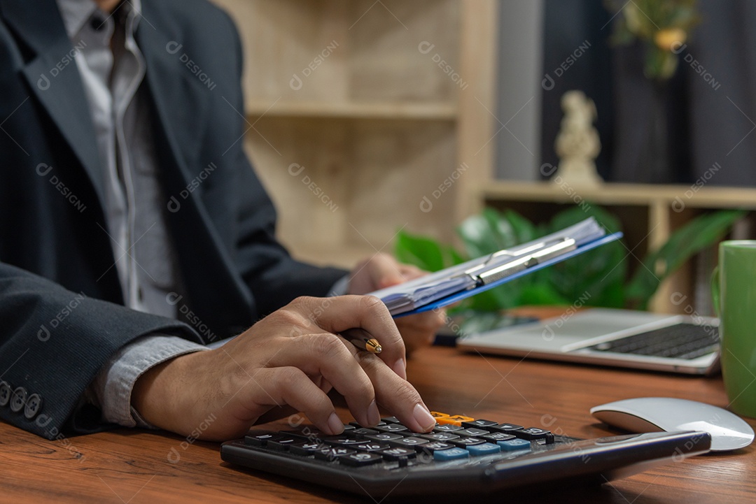 Empresário de mão fazendo finanças e calculando na mesa sobre o custo no escritório em casa.