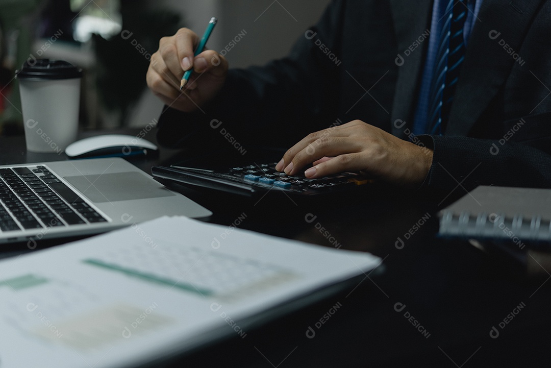 Mão de empresário segurando lápis trabalhando usando calculadora para plano de marketing de análise, relatório de dados de finanças e contabilidade de documentos de negócios e computador portátil em conceitos de escritório.