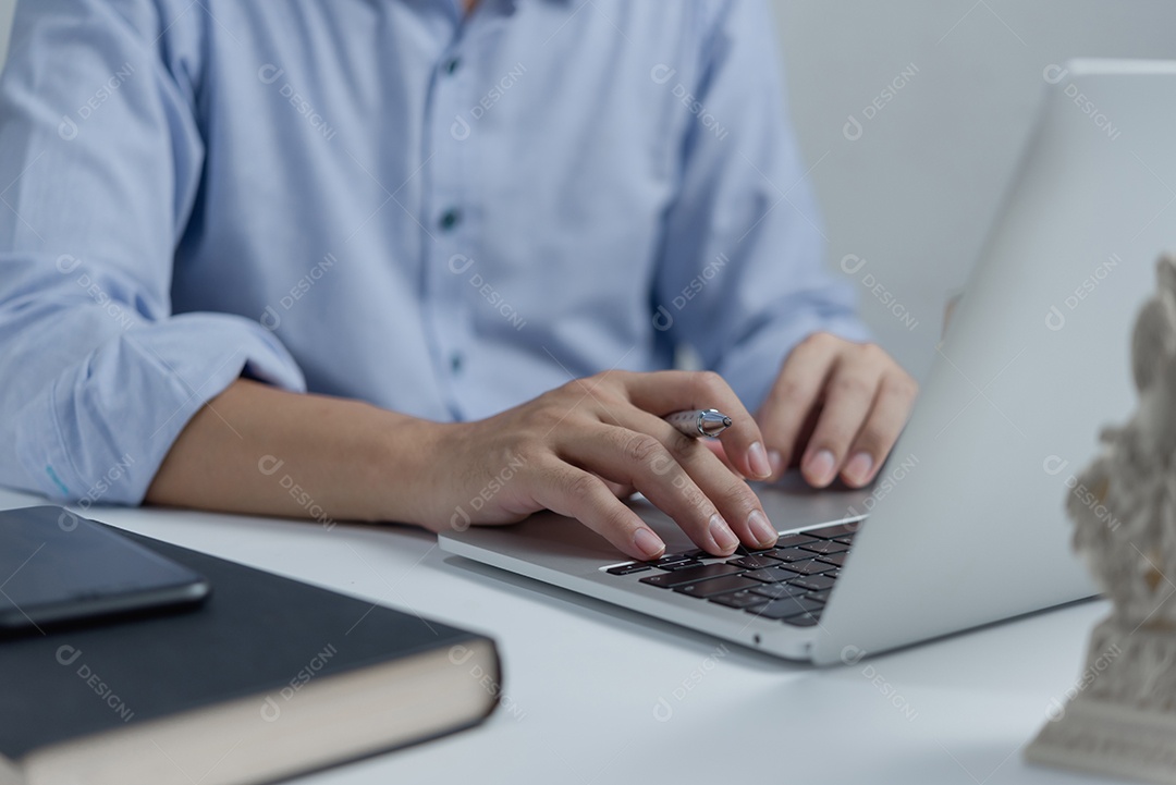 Mãos de empresário trabalhando e digitando no teclado do laptop na mesa.