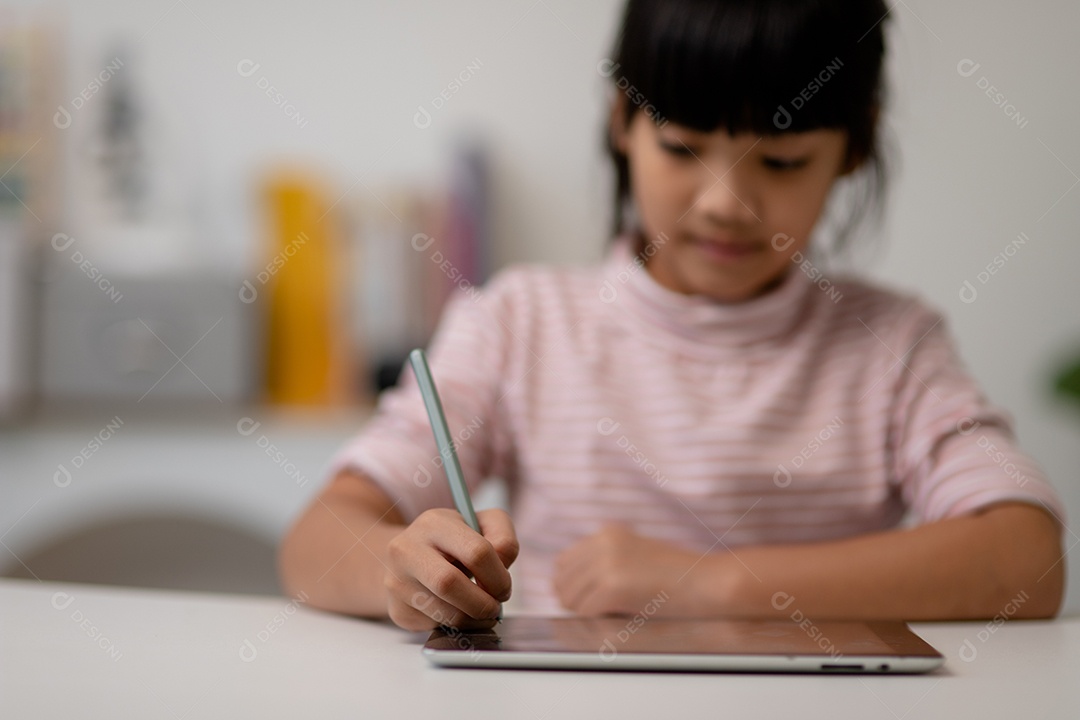 Menina bonita asiática tocando a tela do tablet digital em cima da mesa