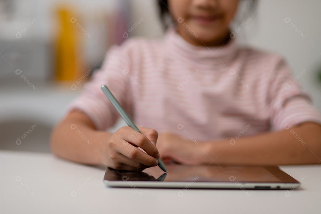 Menina bonita asiática tocando a tela do tablet digital em cima da mesa