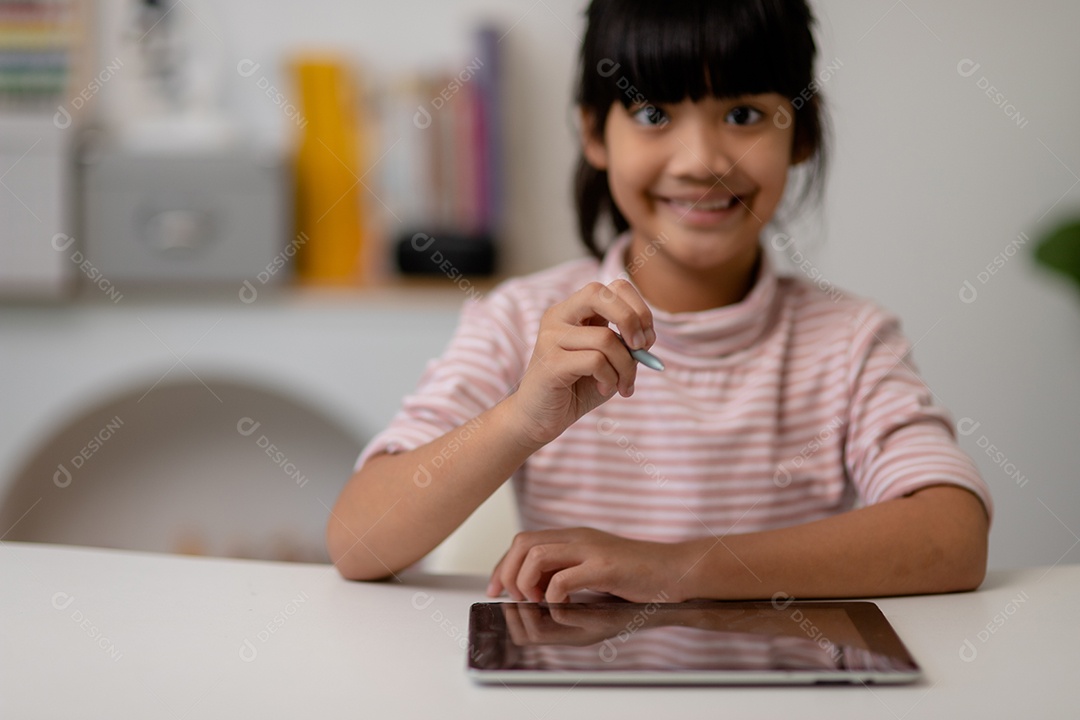 Menina bonita asiática tocando a tela do tablet digital em cima da mesa