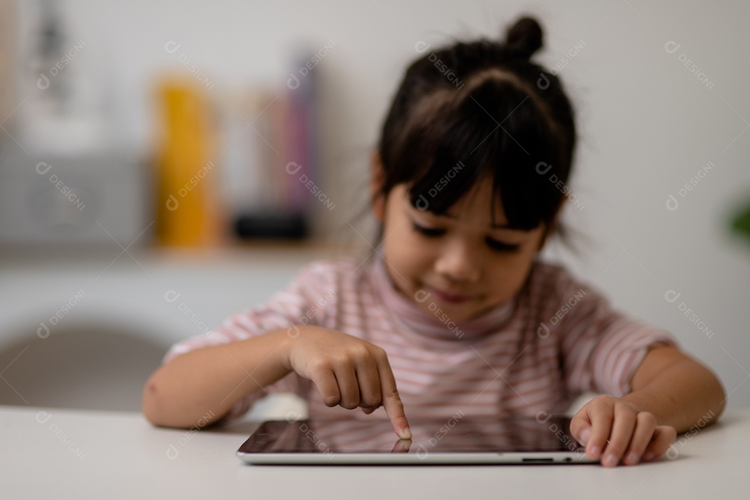 Menina bonita asiática tocando a tela do tablet digital em cima da mesa
