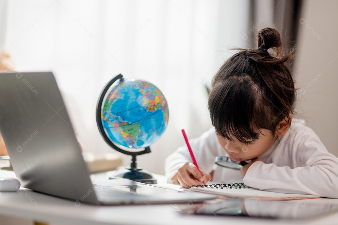 Aluna asiática fazendo sua lição de casa com o laptop em casa. As crianças usam aparelhos para estudar. Educação e ensino a distância para crianças. Educação domiciliar durante a quarentena. Ficar em casa