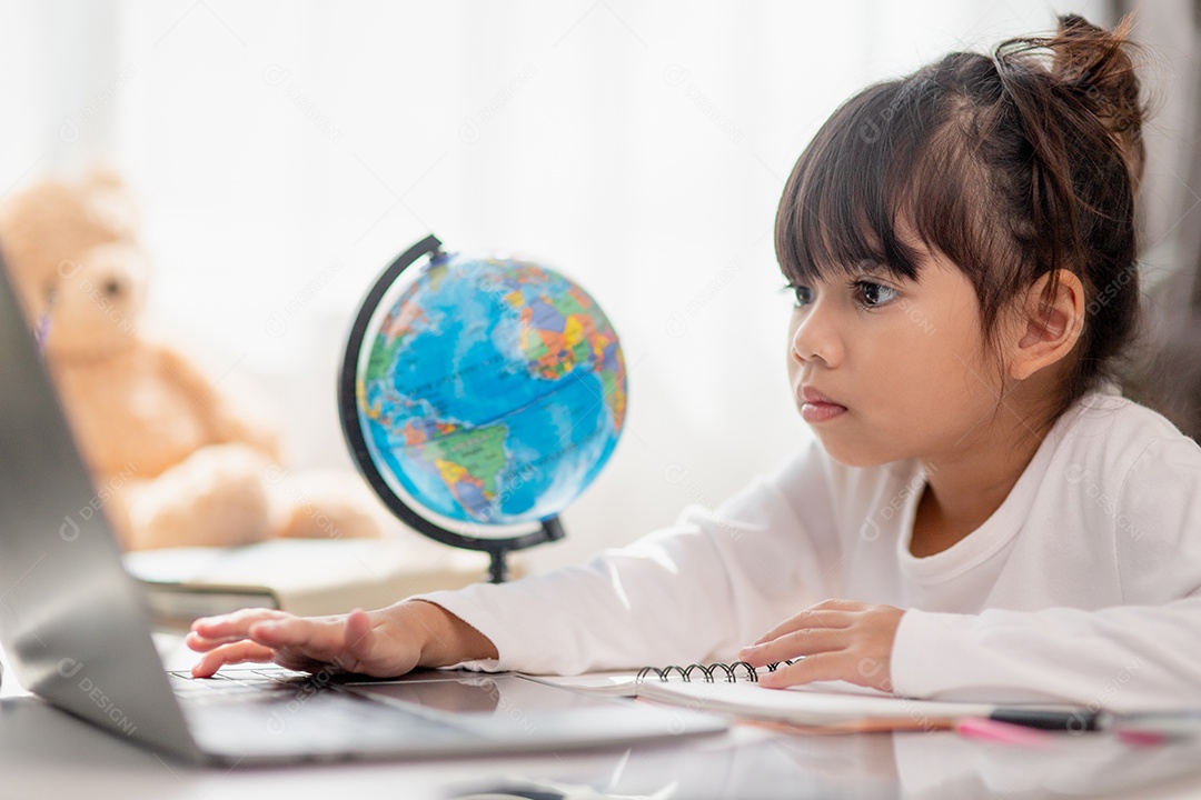 Aluna asiática fazendo sua lição de casa com o laptop em casa. As crianças usam aparelhos para estudar. Educação e ensino a distância para crianças. Educação domiciliar durante a quarentena. Ficar em casa