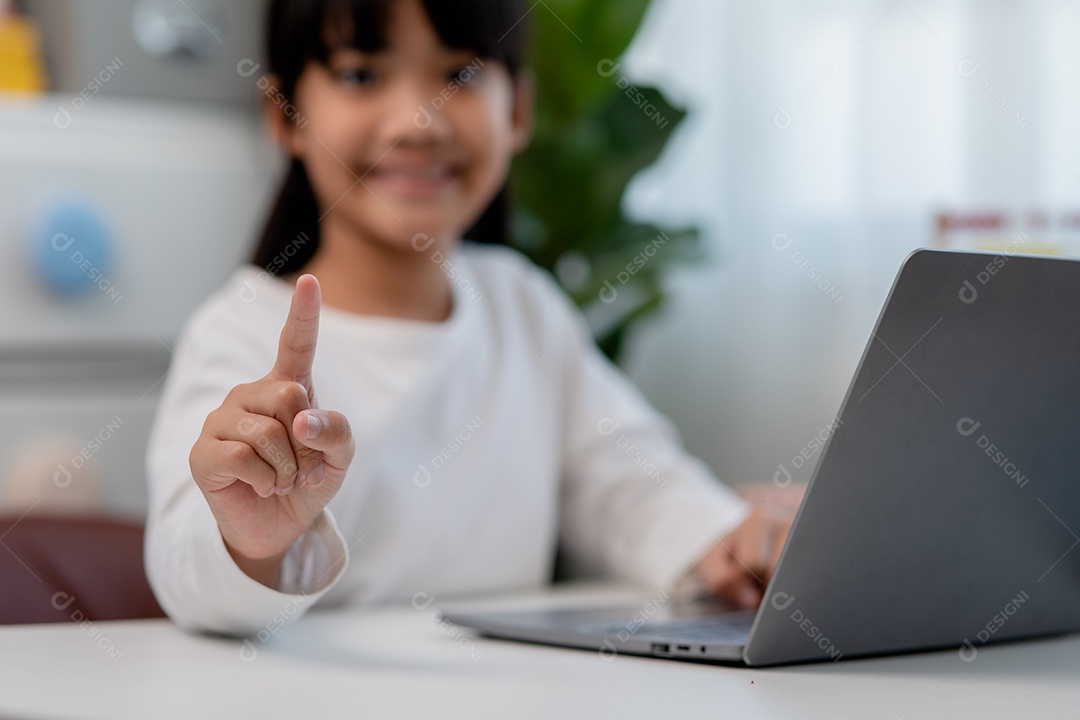 Aluna asiática fazendo sua lição de casa com o laptop em casa. As crianças usam aparelhos para estudar. Educação e ensino a distância para crianças. Educação domiciliar durante a quarentena. Ficar em casa