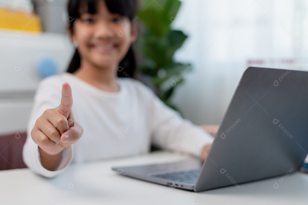 Aluna asiática fazendo sua lição de casa com o laptop em casa. As crianças usam aparelhos para estudar. Educação e ensino a distância para crianças. Educação domiciliar durante a quarentena. Ficar em casa