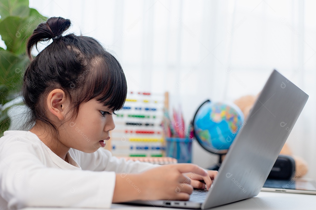 Aluna asiática fazendo sua lição de casa com o laptop em casa. As crianças usam aparelhos para estudar. Educação e ensino a distância para crianças. Educação domiciliar durante a quarentena. Ficar em casa