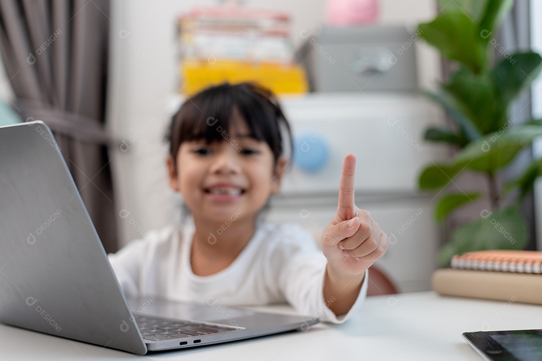 Aluna asiática fazendo sua lição de casa com o laptop em casa. As crianças usam aparelhos para estudar. Educação e ensino a distância para crianças. Educação domiciliar durante a quarentena. Ficar em casa