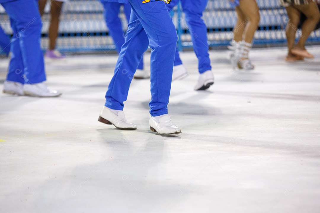 Pernas de um sambista dançando, com calça azul e sapatos brancos no sambódromo da marques de Sapucaí no Rio de Janeiro, Brasil.
