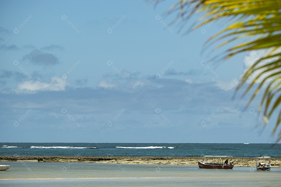 pequenas embarcações paradas em uma piscina natural formada antes da praia