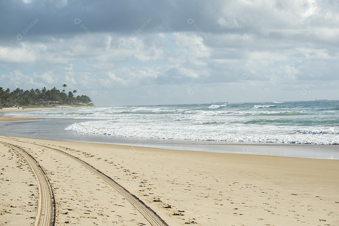 marcas de pneus e pegadas na areia em frente à praia