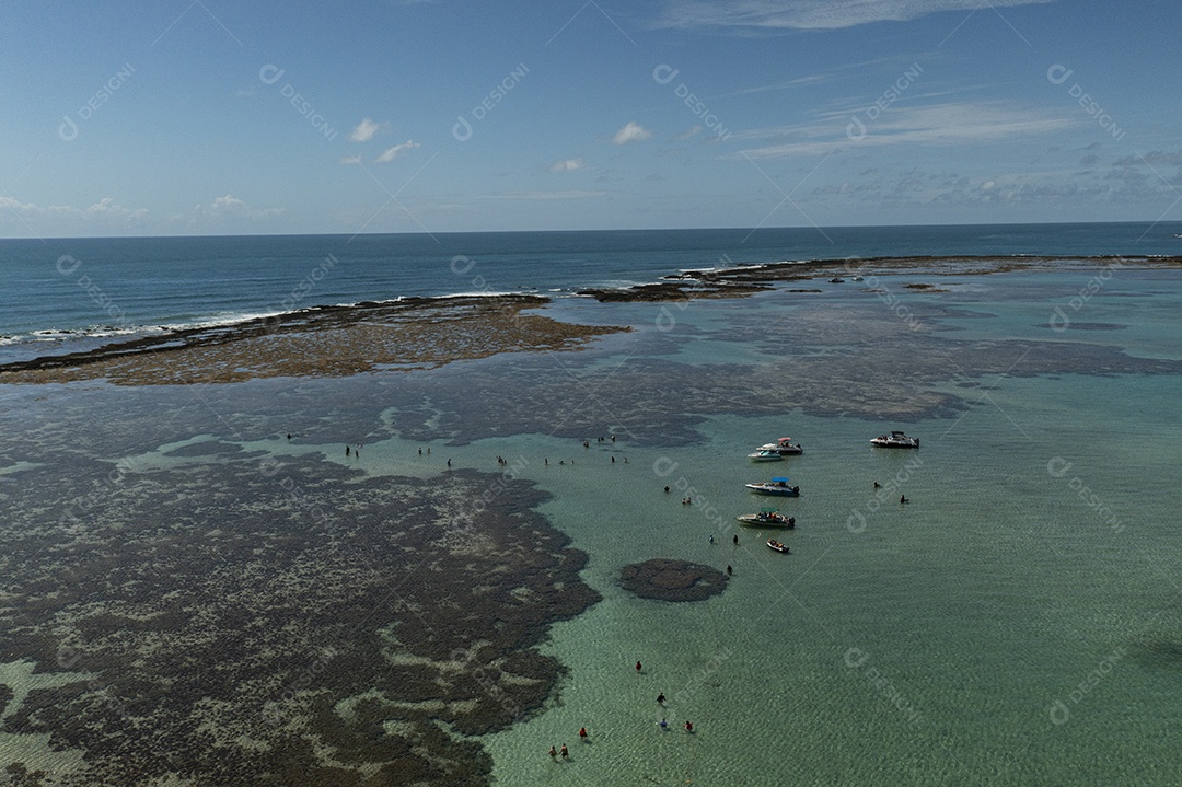 turistas e pequenas embarcações em piscinas naturais formadas por arrecifes