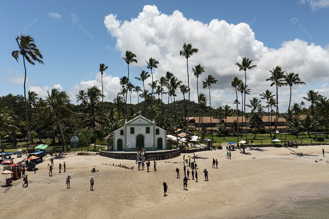 Igreja com coqueiros ao fundo e turistas à frente