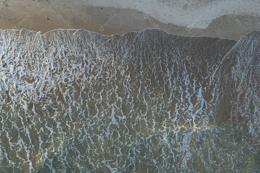 onda de água transparente atingindo a areia da praia e fazendo espuma