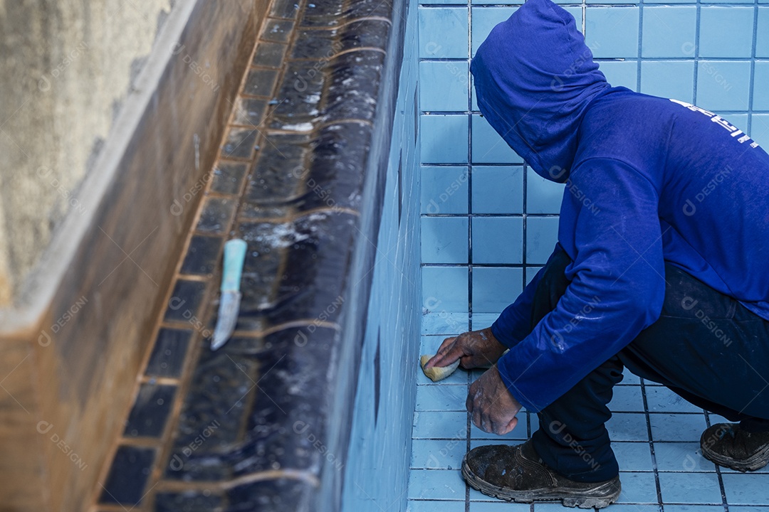 trabalhador com piscina de limpeza de esponja para aplicar rejunte entre telhas