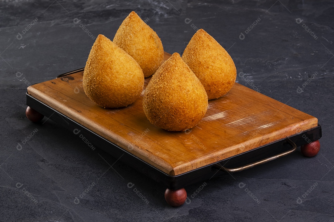 Tradicional coxinha frita em tábua de madeira sobre pedra ardósia