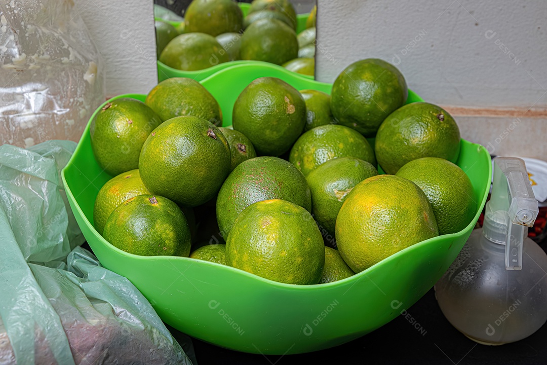 Frutas laranja com casca de cor verde em um recipiente verde.