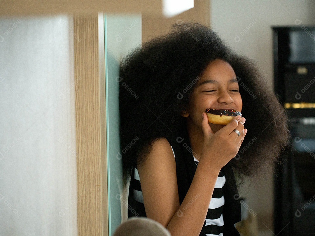 Linda garota negra feliz comendo seu donuts de chocolate