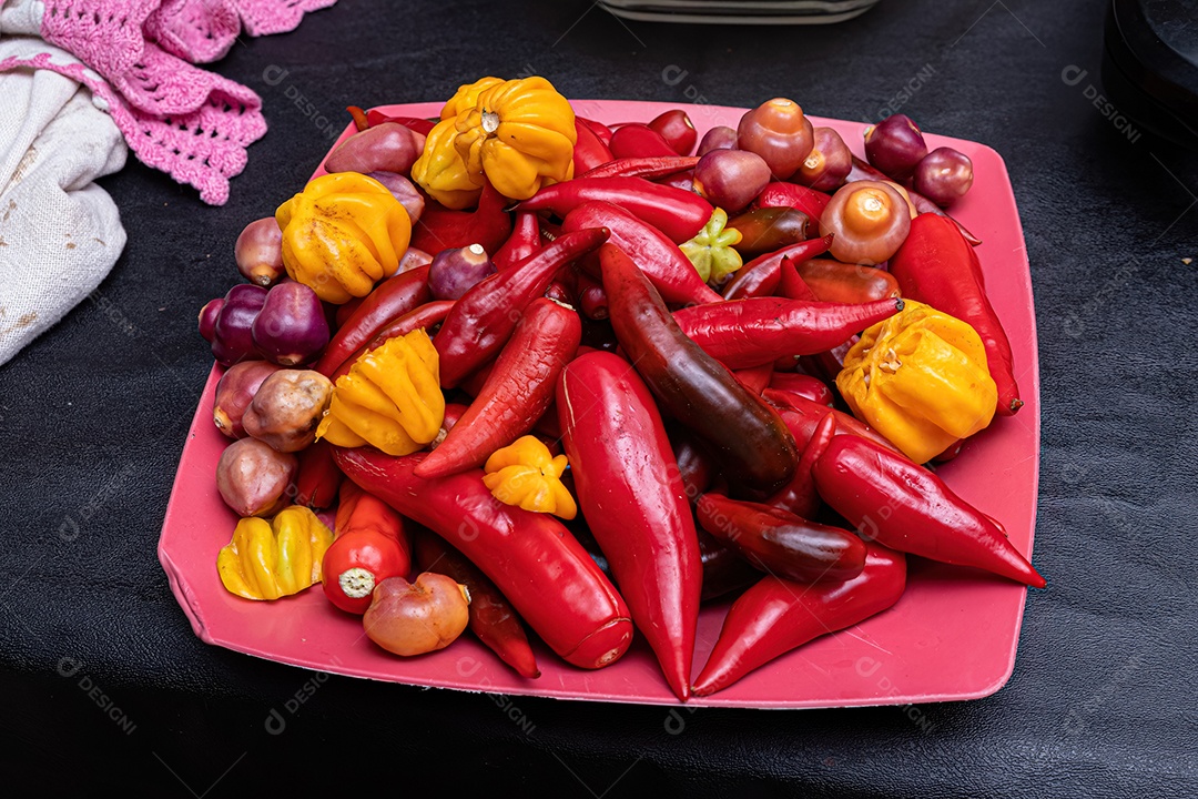 Pimentas pequenas frutas em um prato de plástico vermelho