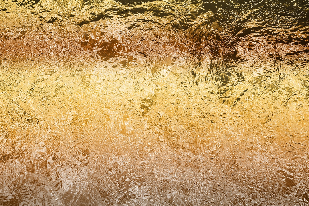 Textura de superfície de água calma transparente turva cor de ouro amarelo claro com salpicos e bolhas. Fundo de natureza abstrata na moda. Ondas de água na luz solar. fundo de água