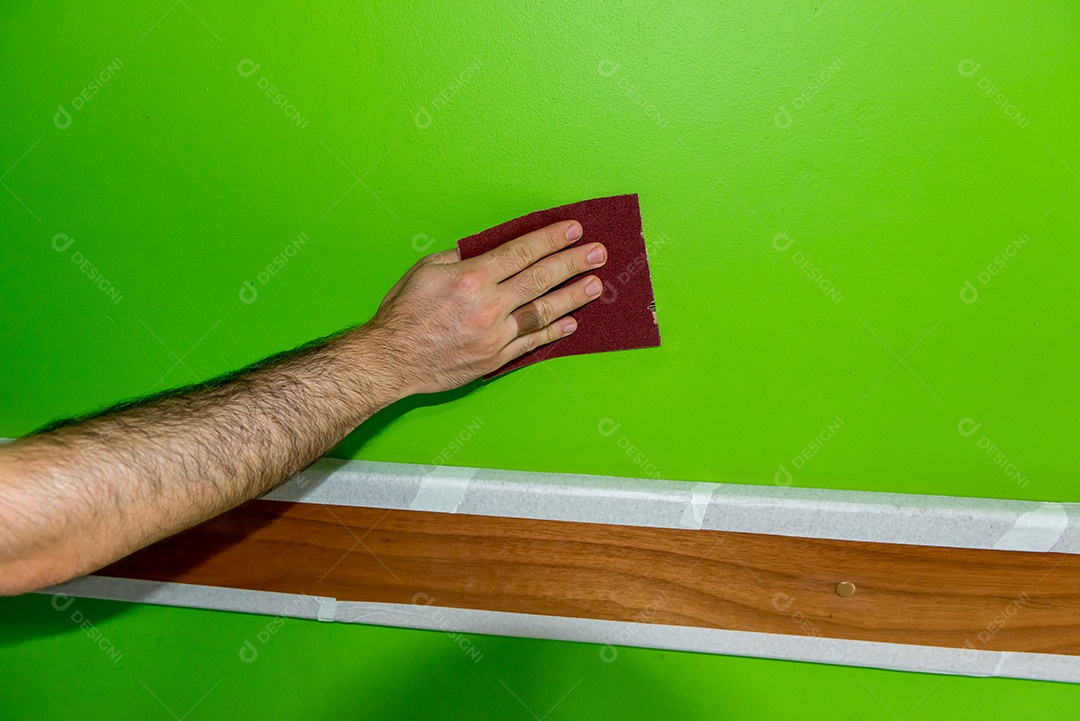 Homem segurando uma lixa depois de lixar a parede verde