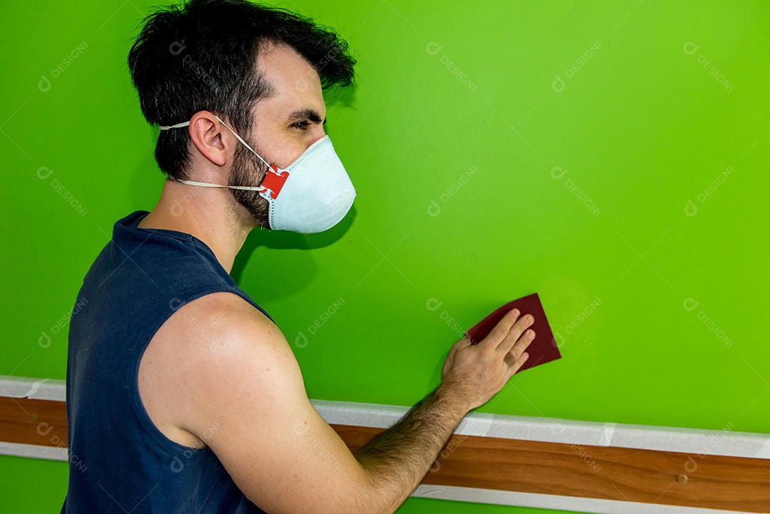 Homem segurando uma lixa depois de lixar a parede verde