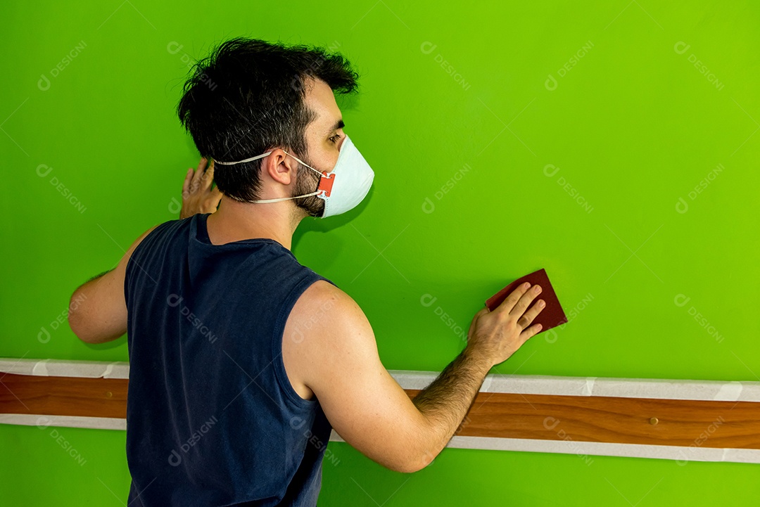 Homem segurando uma lixa depois de lixar a parede verde